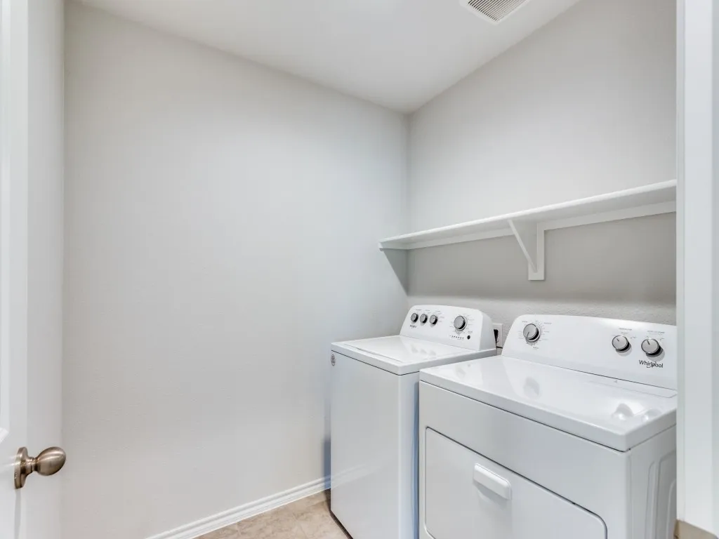 Laundry area featuring neutral wall tones, a built-in storage shelf, and tile flooring