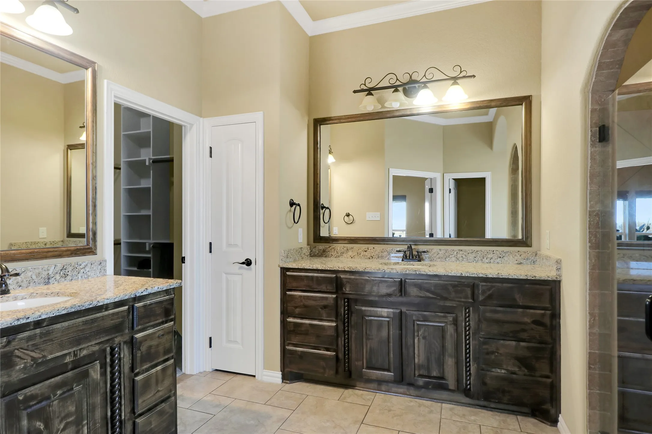 Dual wood-finish vanities with light-toned countertops, integrated sinks, and individual framed mirrors