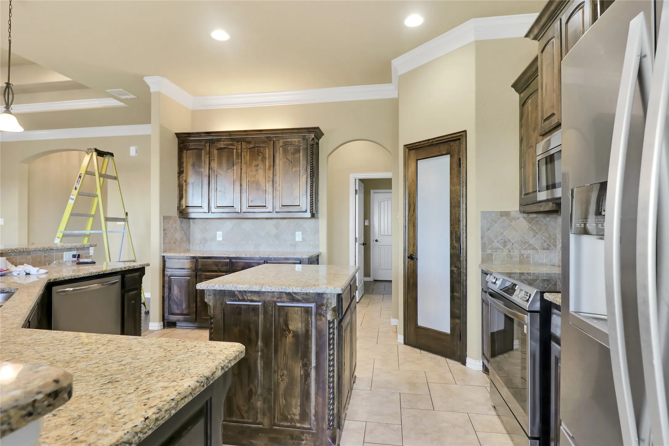 Kitchen featuring granite countertops, dark wood cabinetry, stainless steel appliances, tile flooring, and recessed lighting