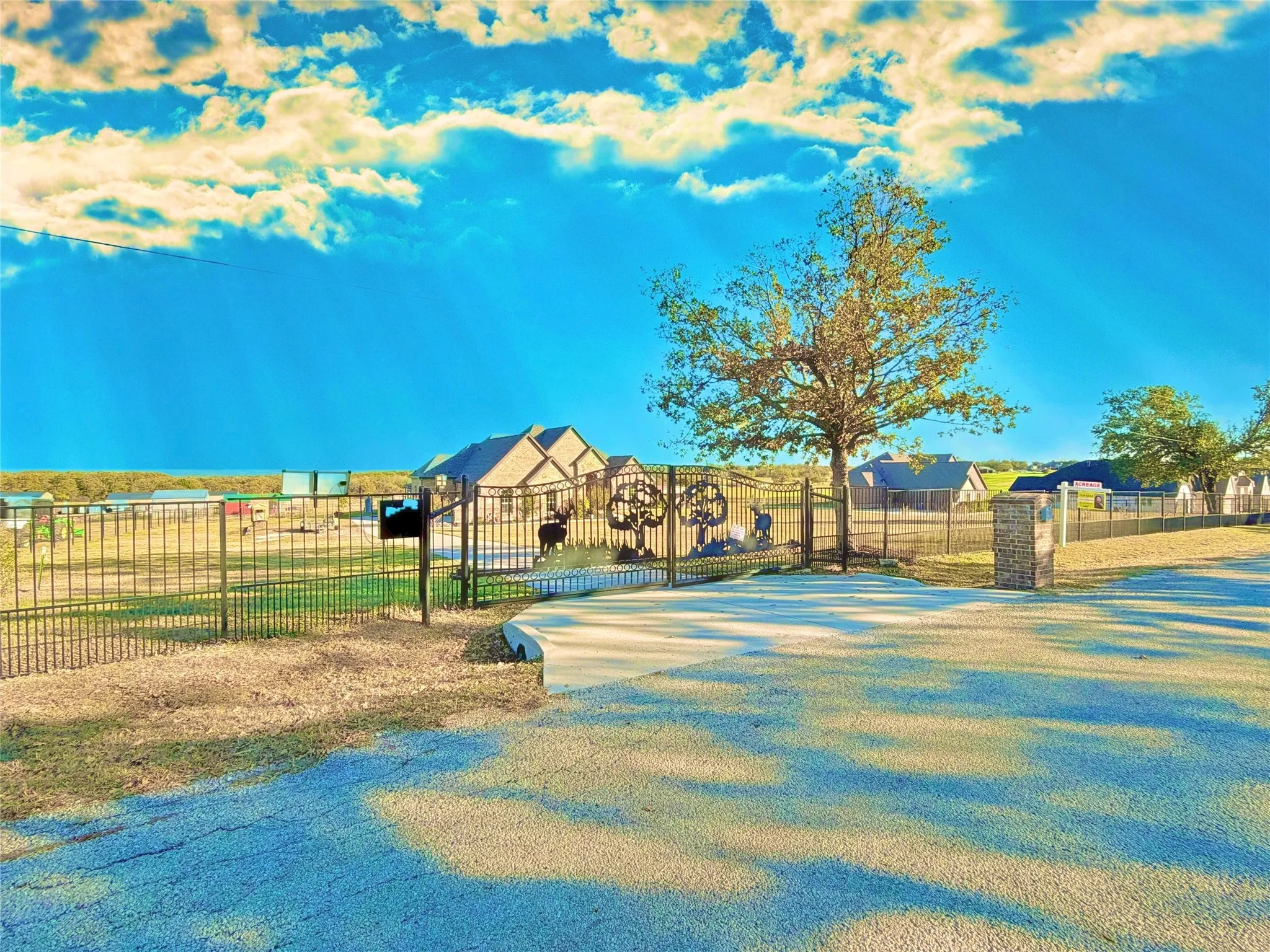 Gated entrance with decorative ironwork, brick columns, and a paved driveway