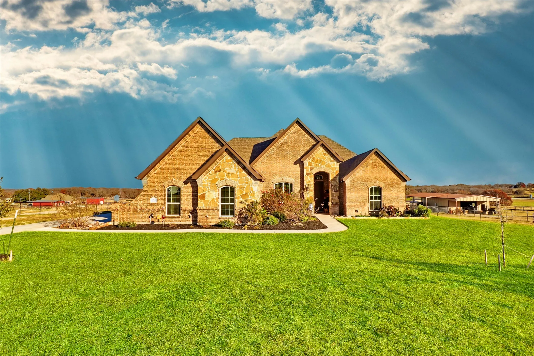 Brick and stone exterior with architectural gables, arched entry, and manicured landscaping