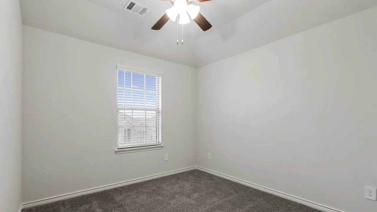 Recessed window with blinds, overhead ceiling fan, and grey carpeting