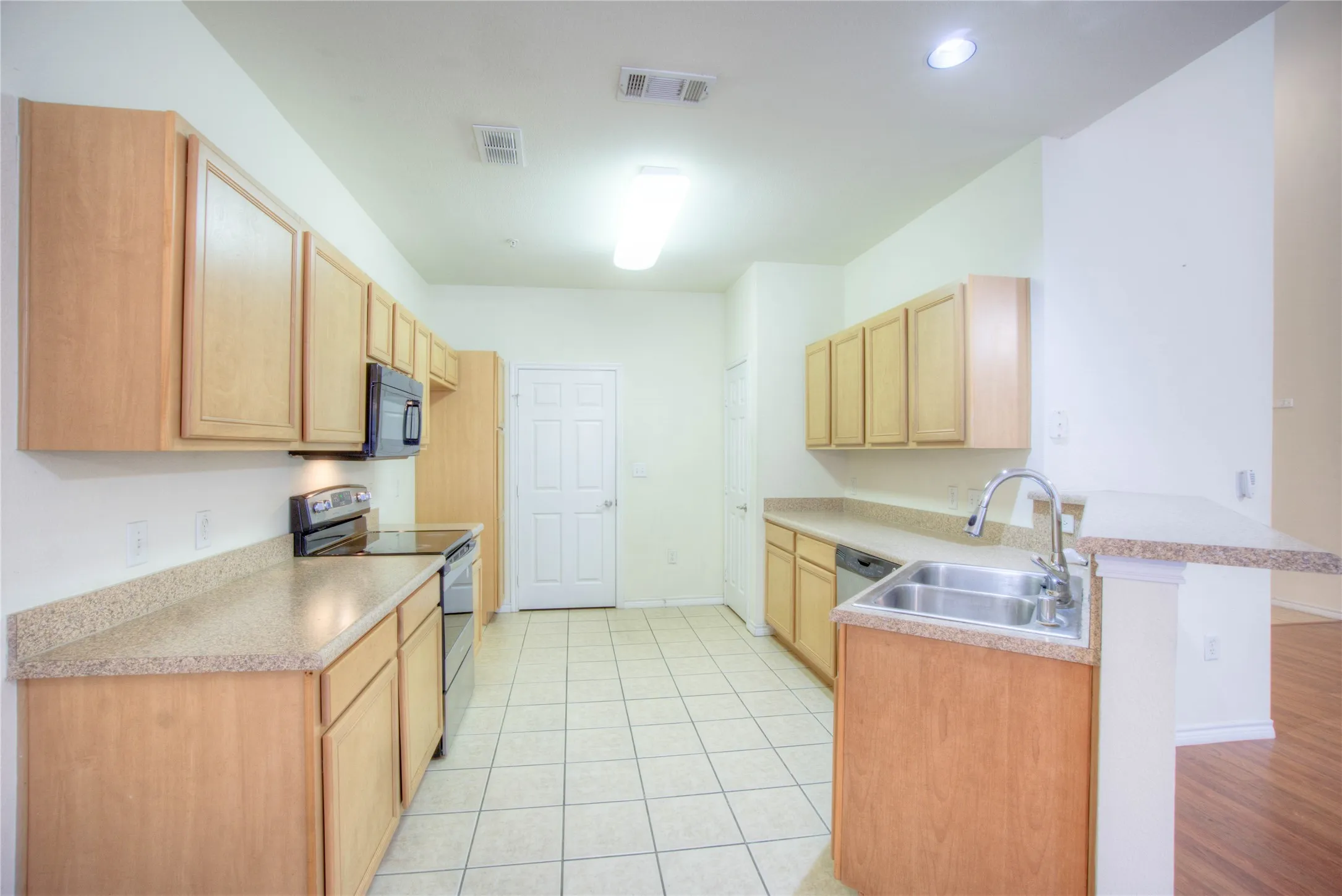 Kitchen featuring wood-finish cabinetry, light-toned countertops, and tile flooring