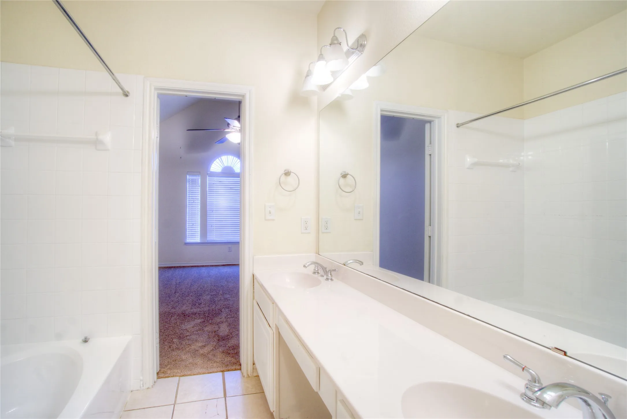 Dual vanity with integrated sinks, full-width mirror, and overhead vanity lighting