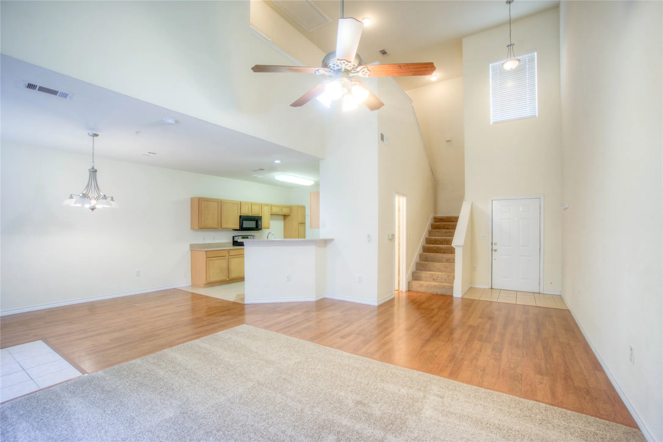Vaulted ceilings with a ceiling fan, wood-finish flooring, and a chandelier