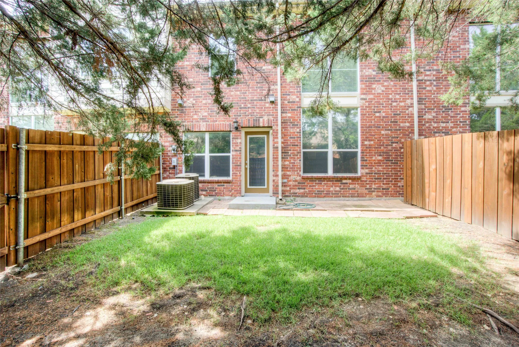 Brick exterior, private fenced yard, grass area, patio, and ground-level windows