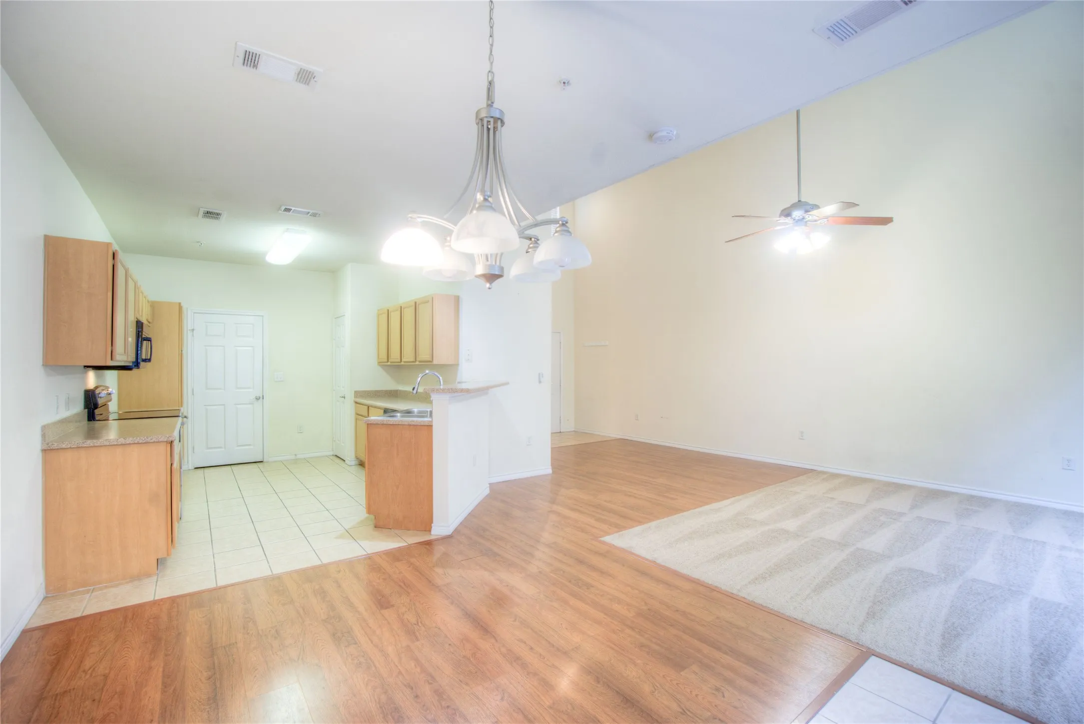 Open-concept living area with wood-finish flooring, a ceiling fan, and an integrated kitchen