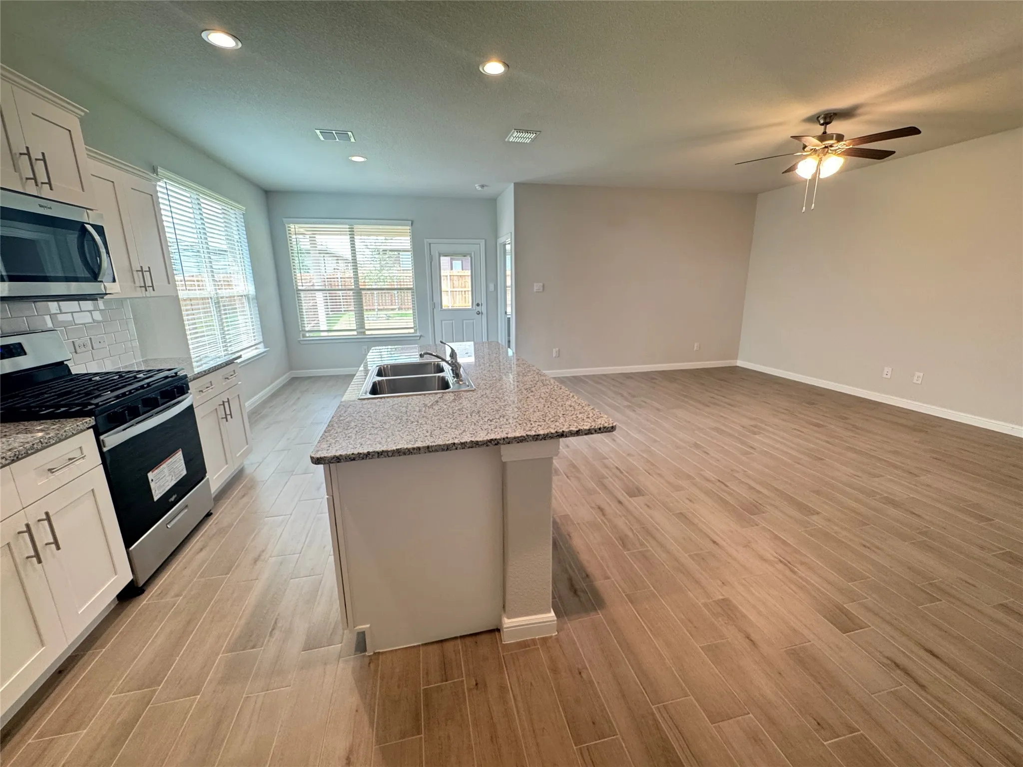 Kitchen featuring stainless steel appliances, a sink, baseboards, light wood-style flooring, and ceiling fan