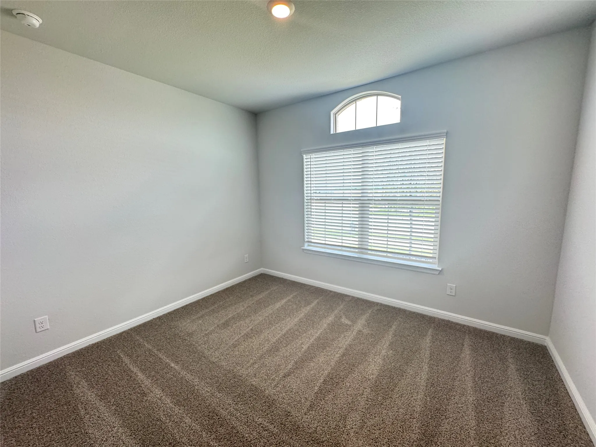 Unfurnished room with dark carpet, a smoke detector, and baseboards