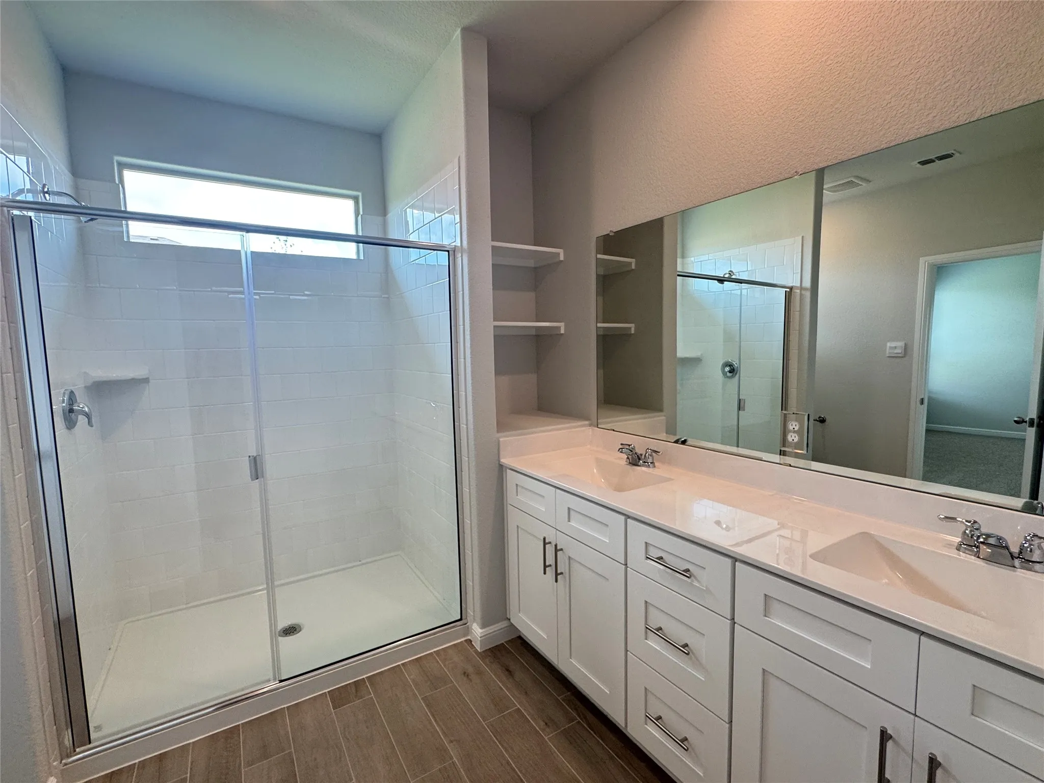 Bathroom with double vanity, a shower stall, and wood finished floors
