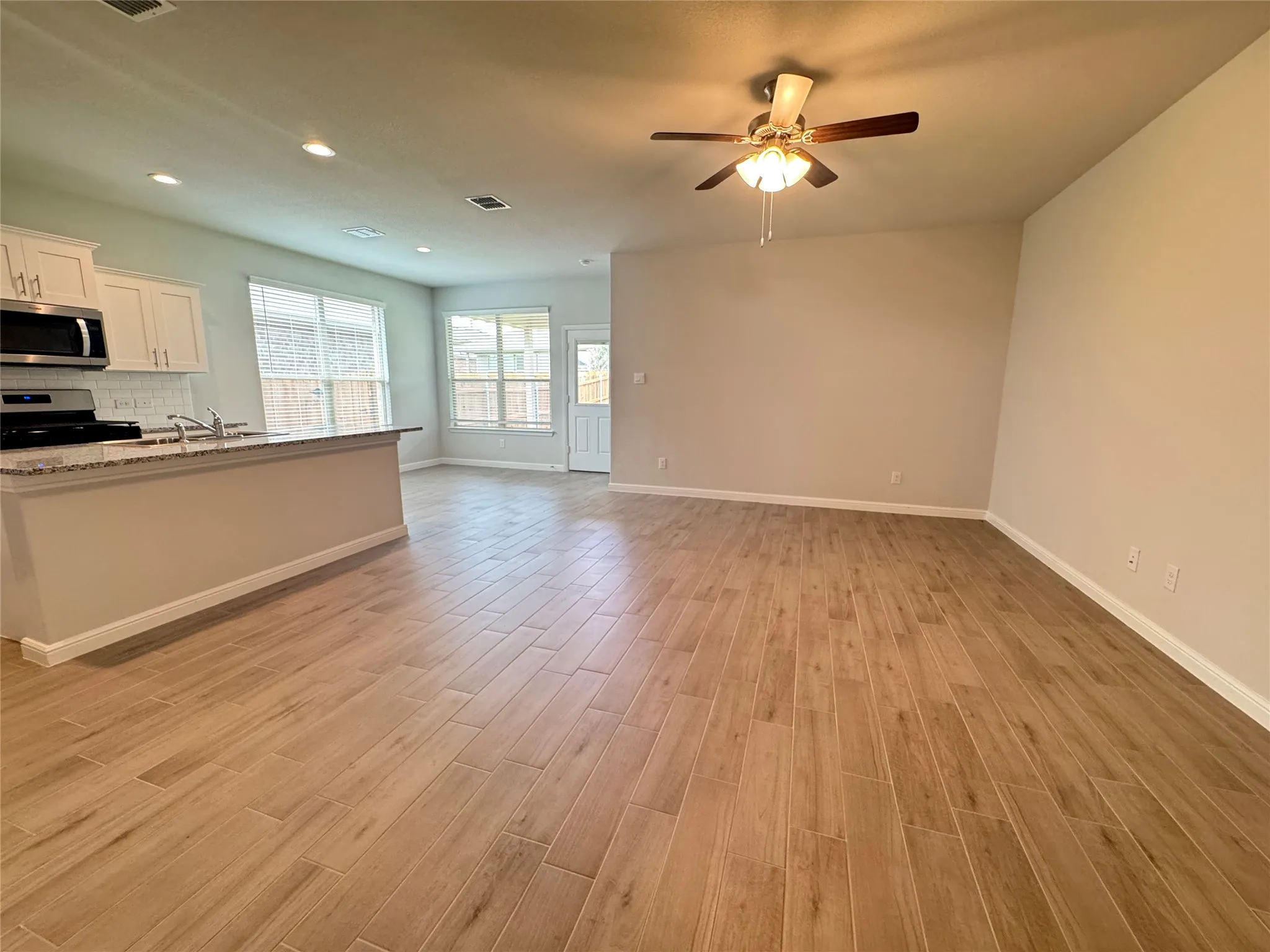 Unfurnished living room with light wood-style floors, baseboards, a ceiling fan, and recessed lighting