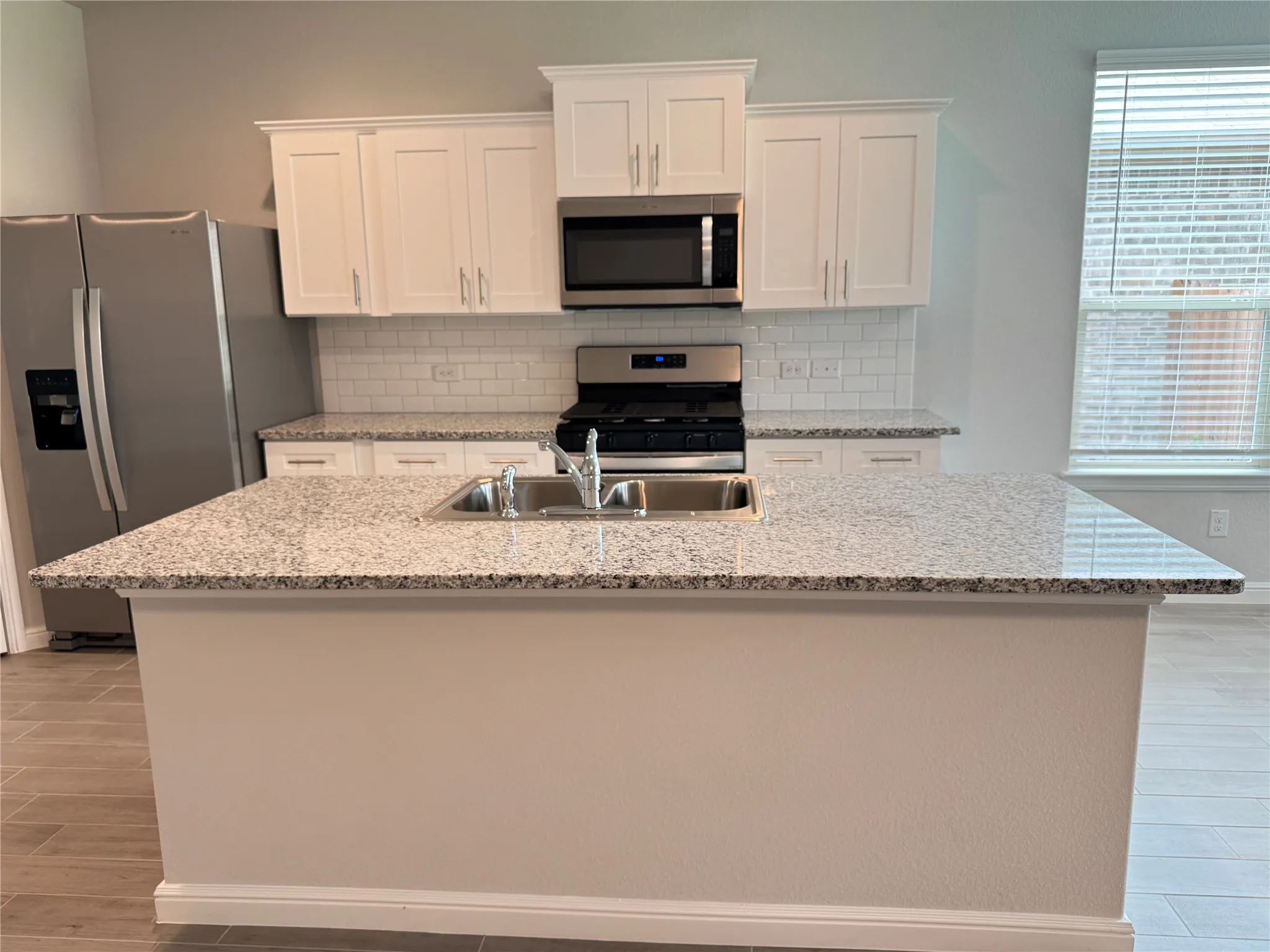 Kitchen featuring appliances with stainless steel finishes, a sink, backsplash, and white cabinets