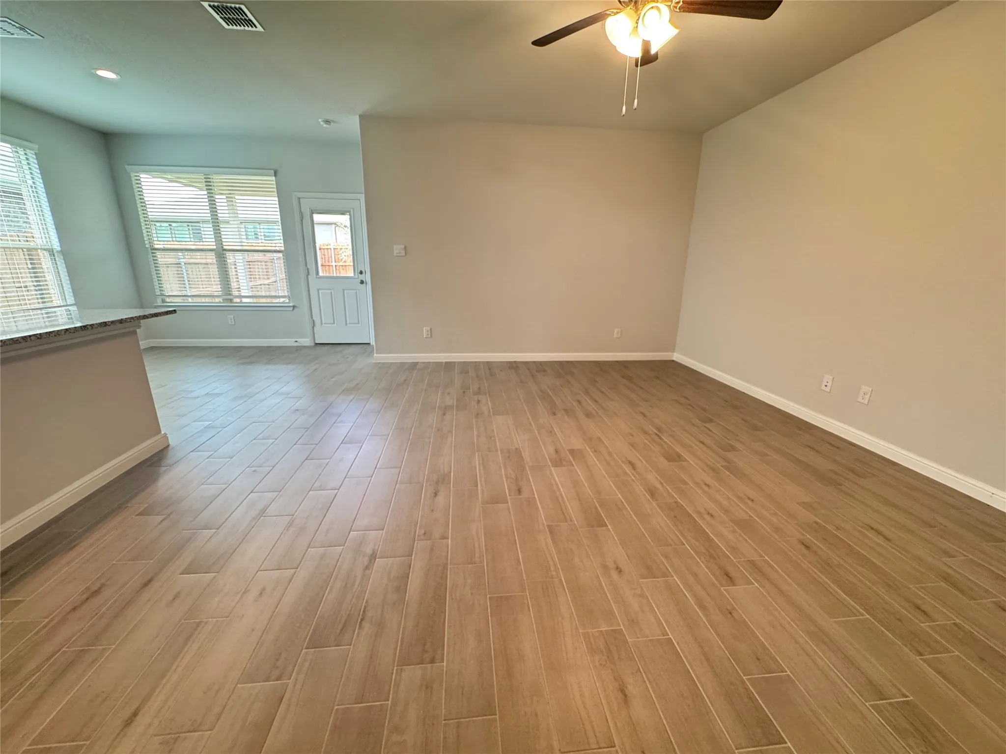Unfurnished living room featuring a ceiling fan, baseboards, and light wood finished floors