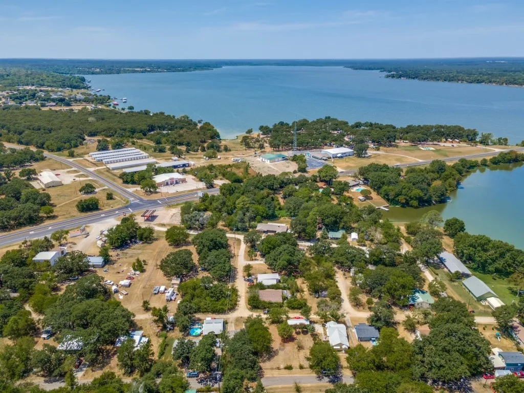Expansive water body, verdant shoreline, mature trees, roads, and structures