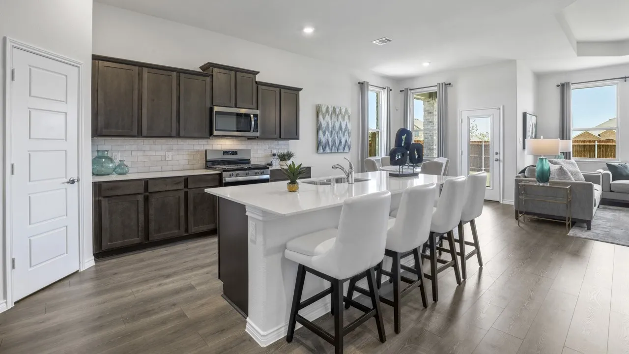 Open-concept kitchen featuring dark wood cabinetry, white subway tile backsplash, stainless steel appliances, and an island with a white countertop