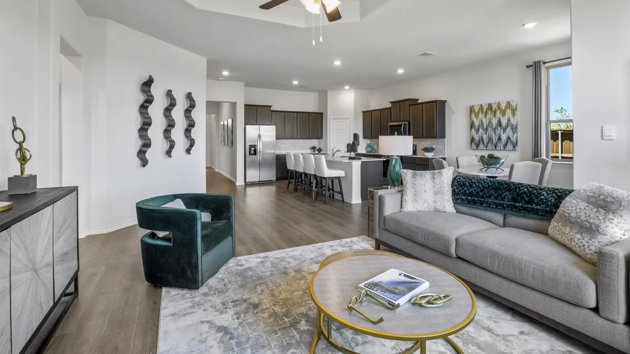 Open-concept living area with wood-finish flooring, a ceiling fan, recessed lighting, and a kitchen featuring a central island with bar seating and dark cabinetry