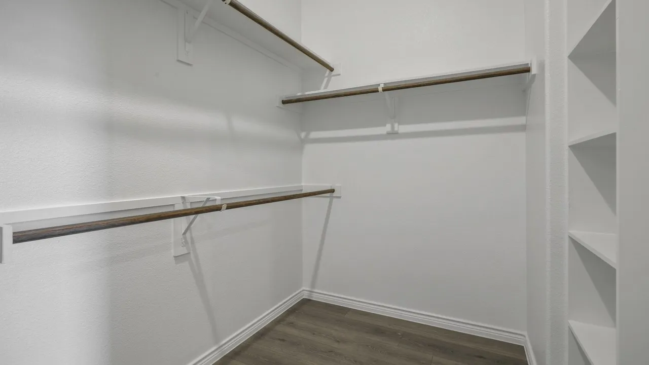 Built-in shelving, multiple hanging rods, and wood-finish flooring