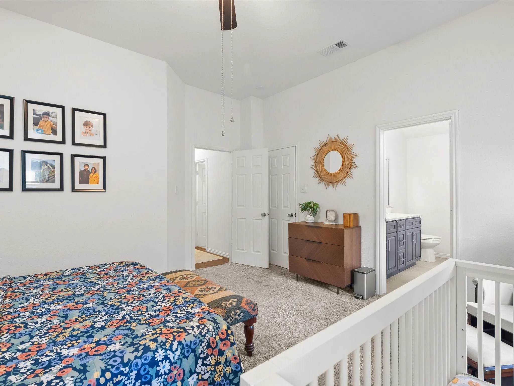 Carpeted flooring throughout, with ceiling fan, white paneled doors, and white balustrade