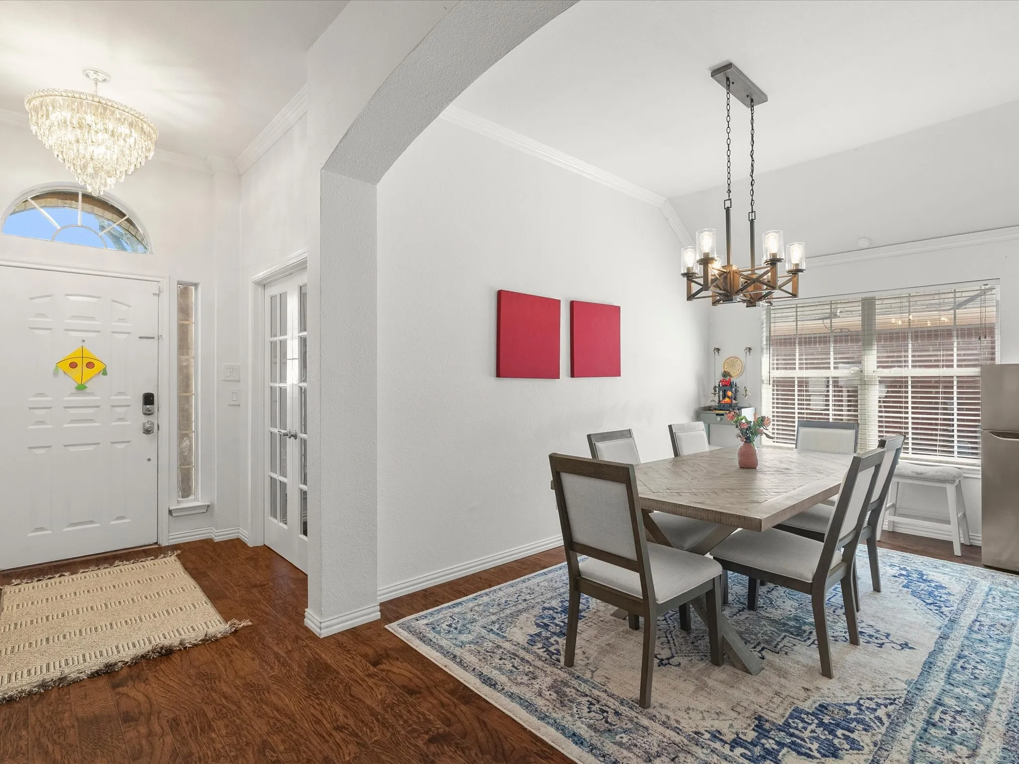 Wood-finish flooring throughout, arched entryway, white paneled entry door with transom window, French doors, and recessed lighting