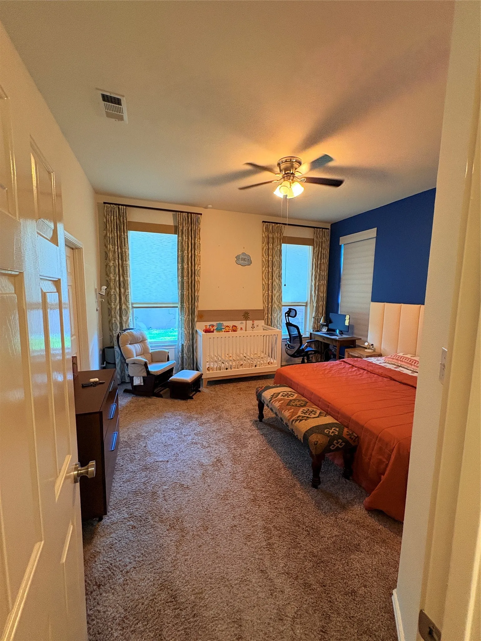 Room with plush carpet flooring, two windows with blinds, and a ceiling fan with integrated lighting