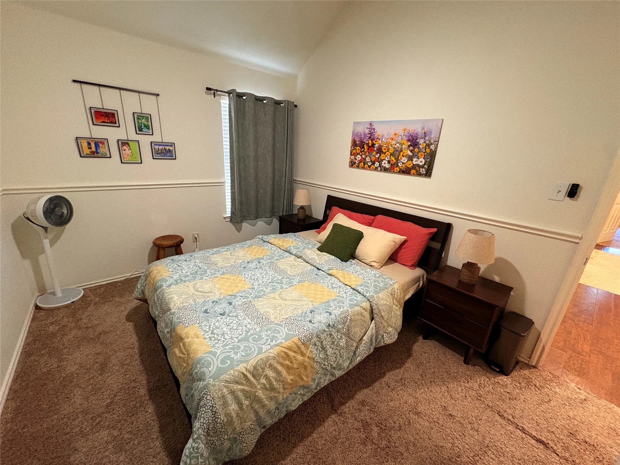 Vaulted ceiling with textured wall finish and chair rail molding, plush carpet flooring, and window with blinds