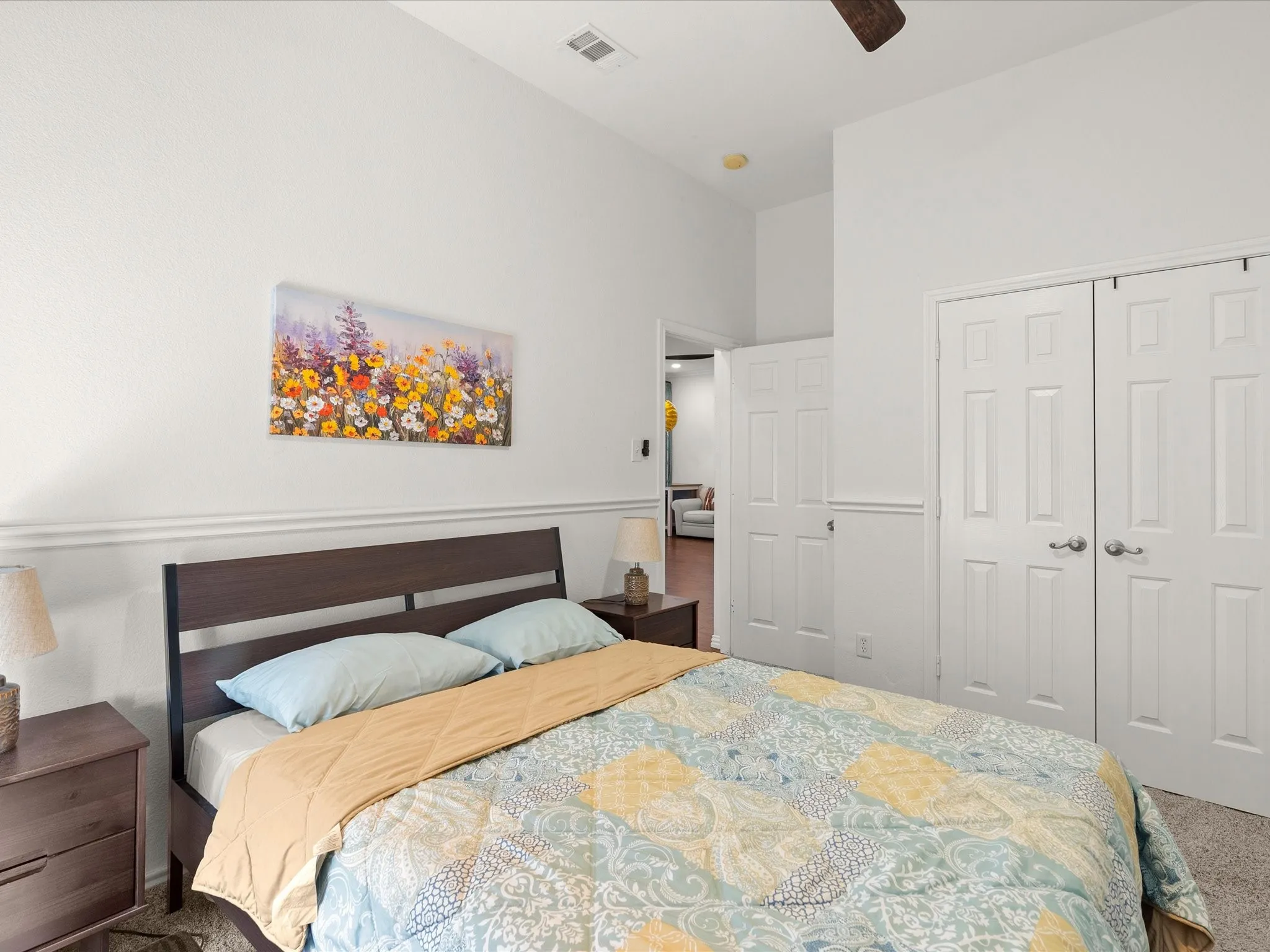 Vaulted ceiling with a ceiling fan, white paneled doors, and wainscoting