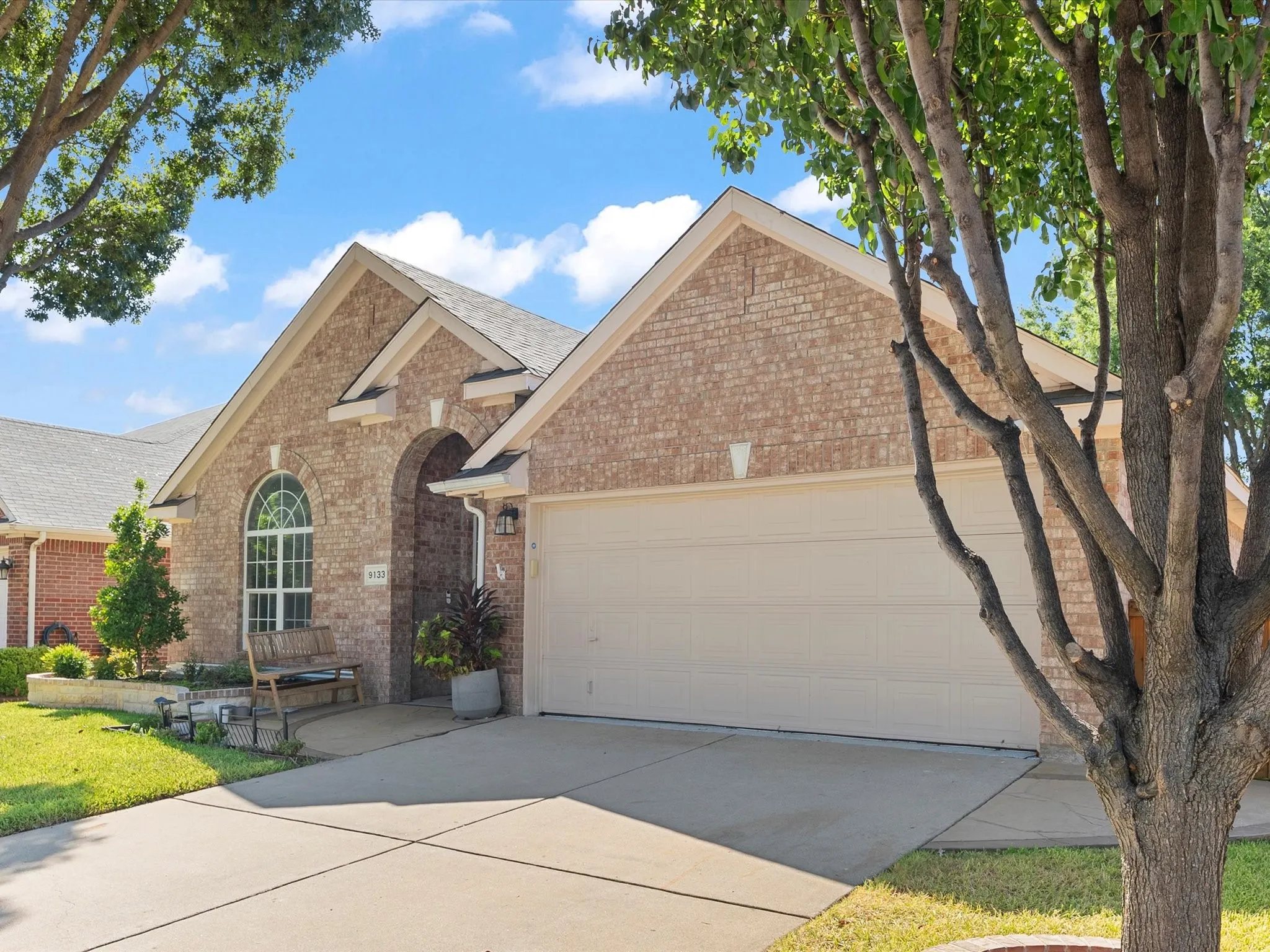 Brick facade with arched entry, an integrated two-car garage, and a concrete driveway