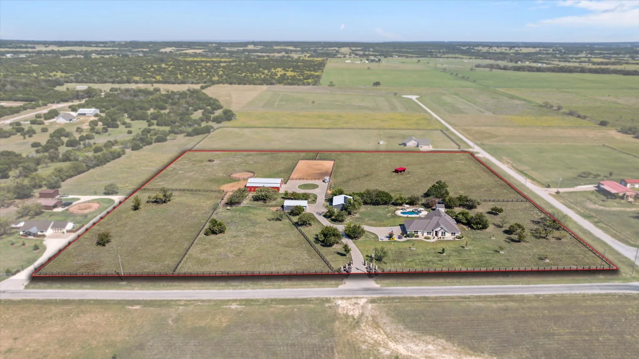 Expansive rural property featuring a main residence, a swimming pool, multiple outbuildings, and fenced pastures