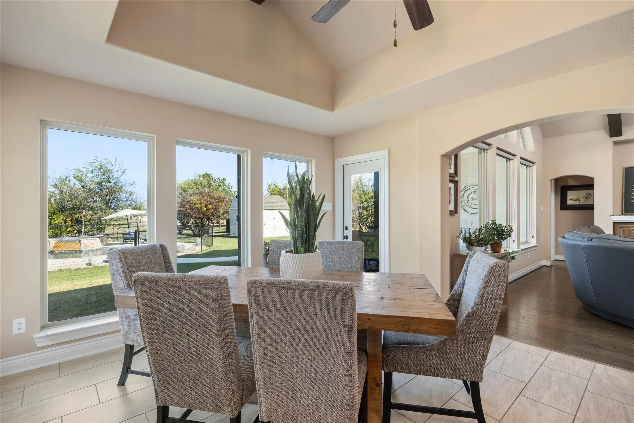 Vaulted ceiling with a ceiling fan, arched doorway, and multiple large windows