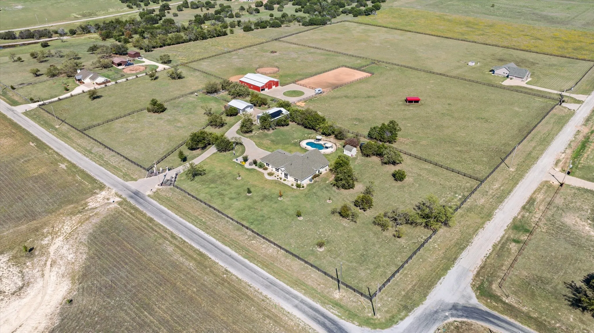 Expansive property featuring a main residence, two red outbuildings, and a private swimming pool