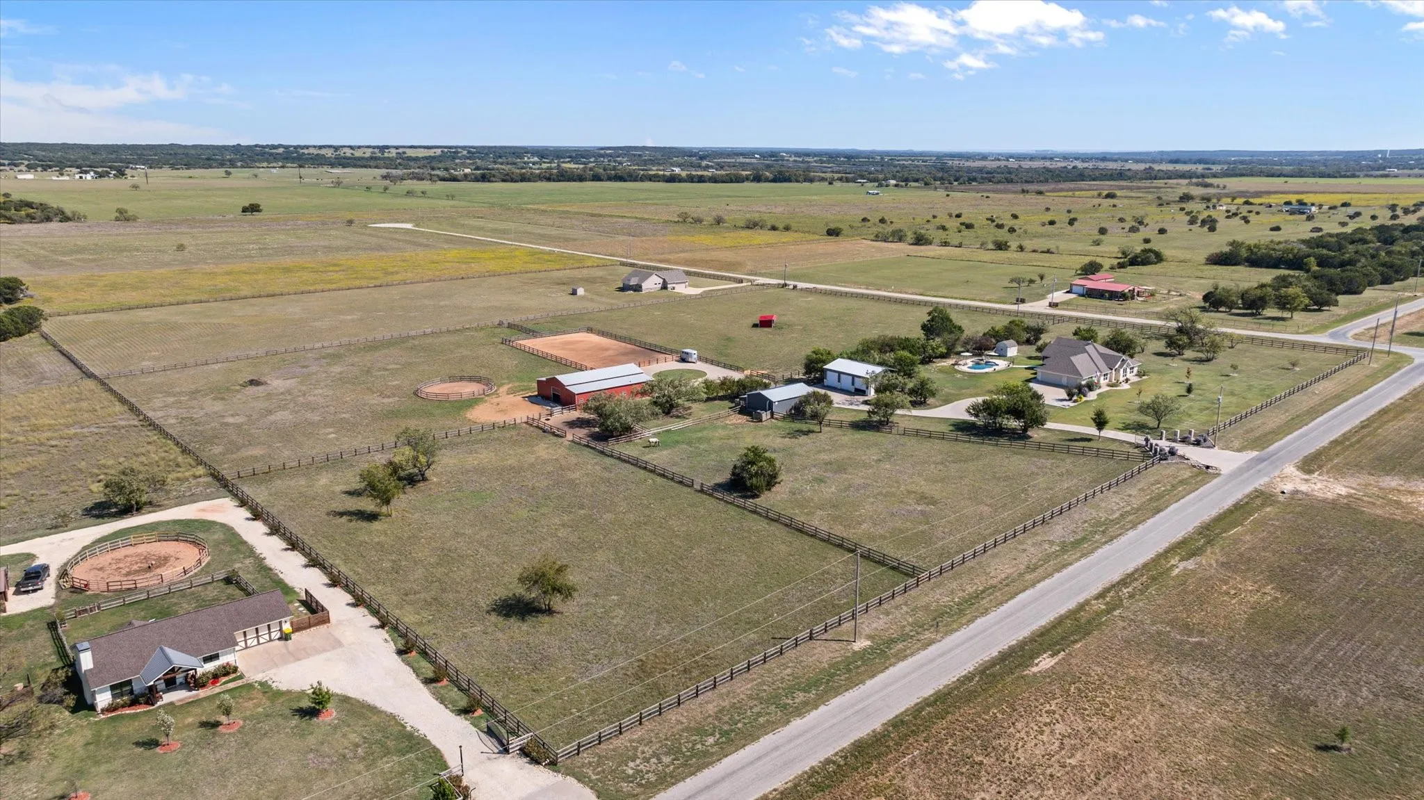 Expansive property with a main residence, swimming pool, and multiple outbuildings, including a red barn and smaller structures