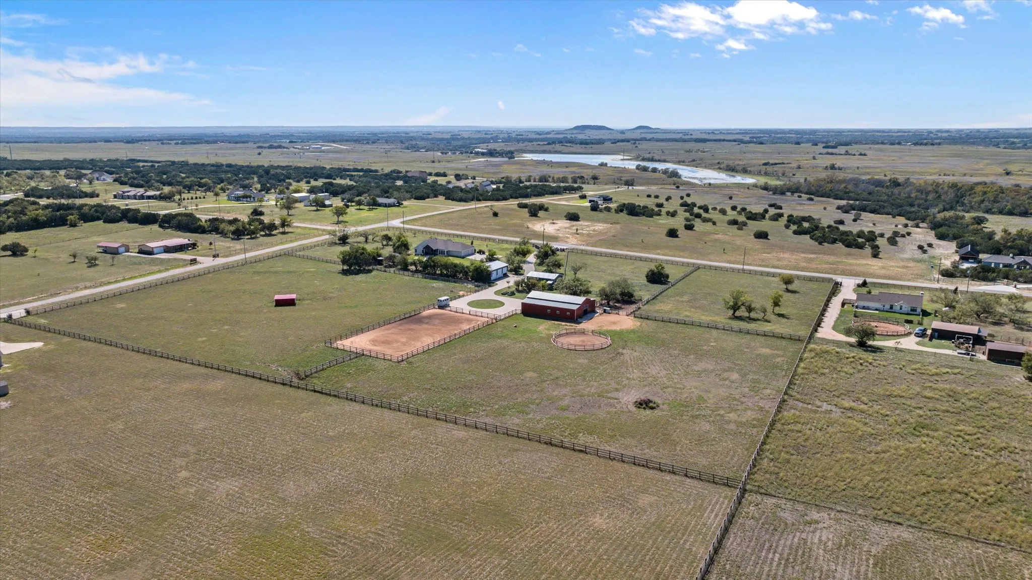 Expansive property featuring fenced pastures, a barn, and multiple outbuildings
