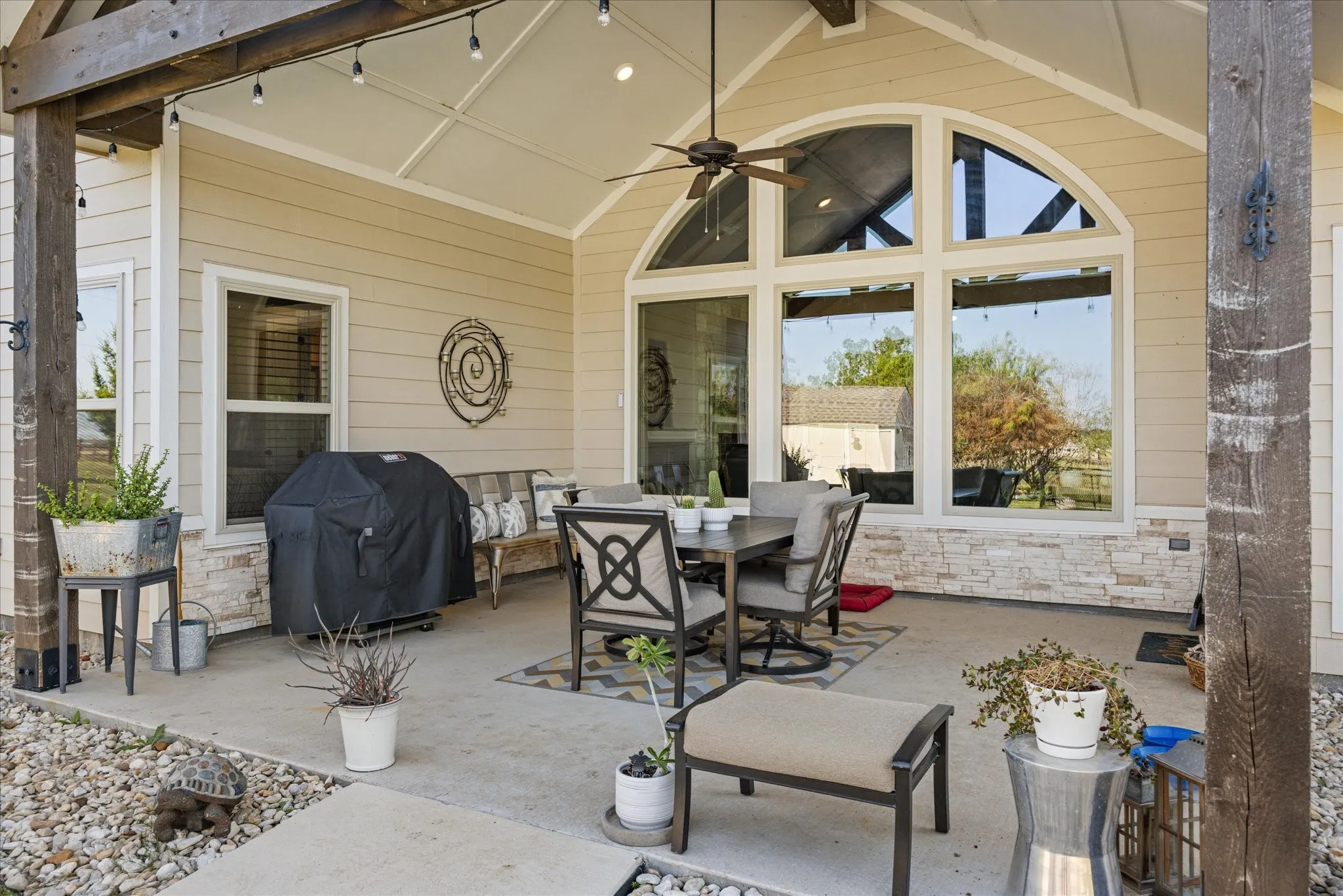Covered patio with a vaulted ceiling, exposed wood beams, and a ceiling fan