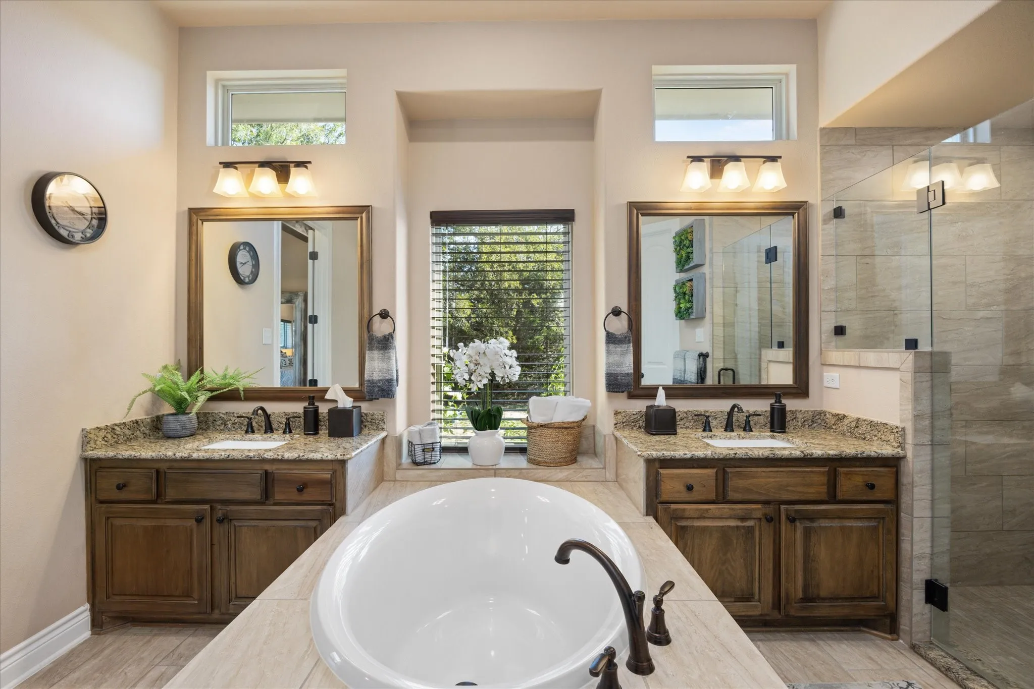 Dual vanities with granite countertops, wood-finish cabinetry, and framed mirrors
