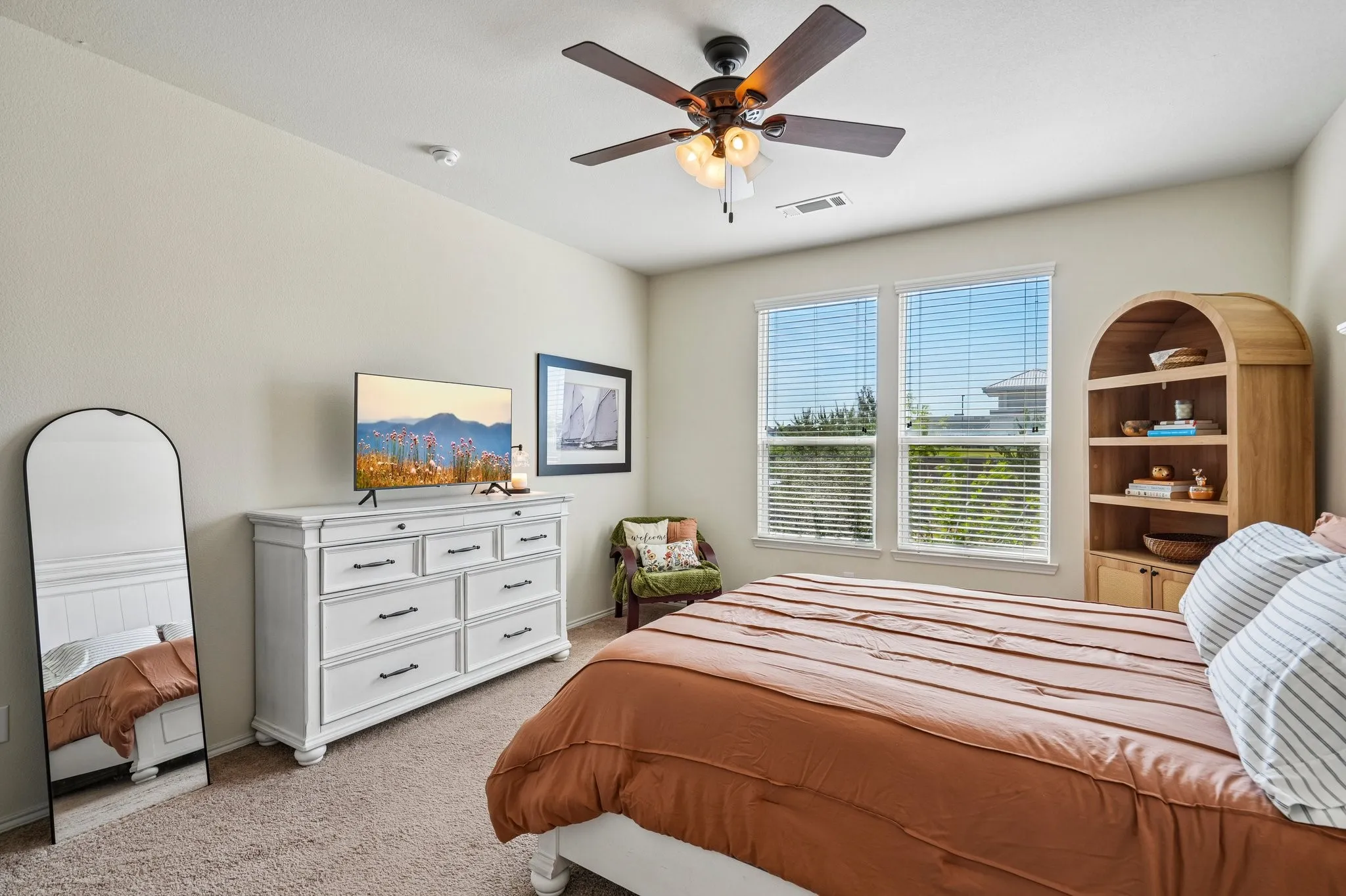 Bright room with a ceiling fan, two windows, and textured carpeting