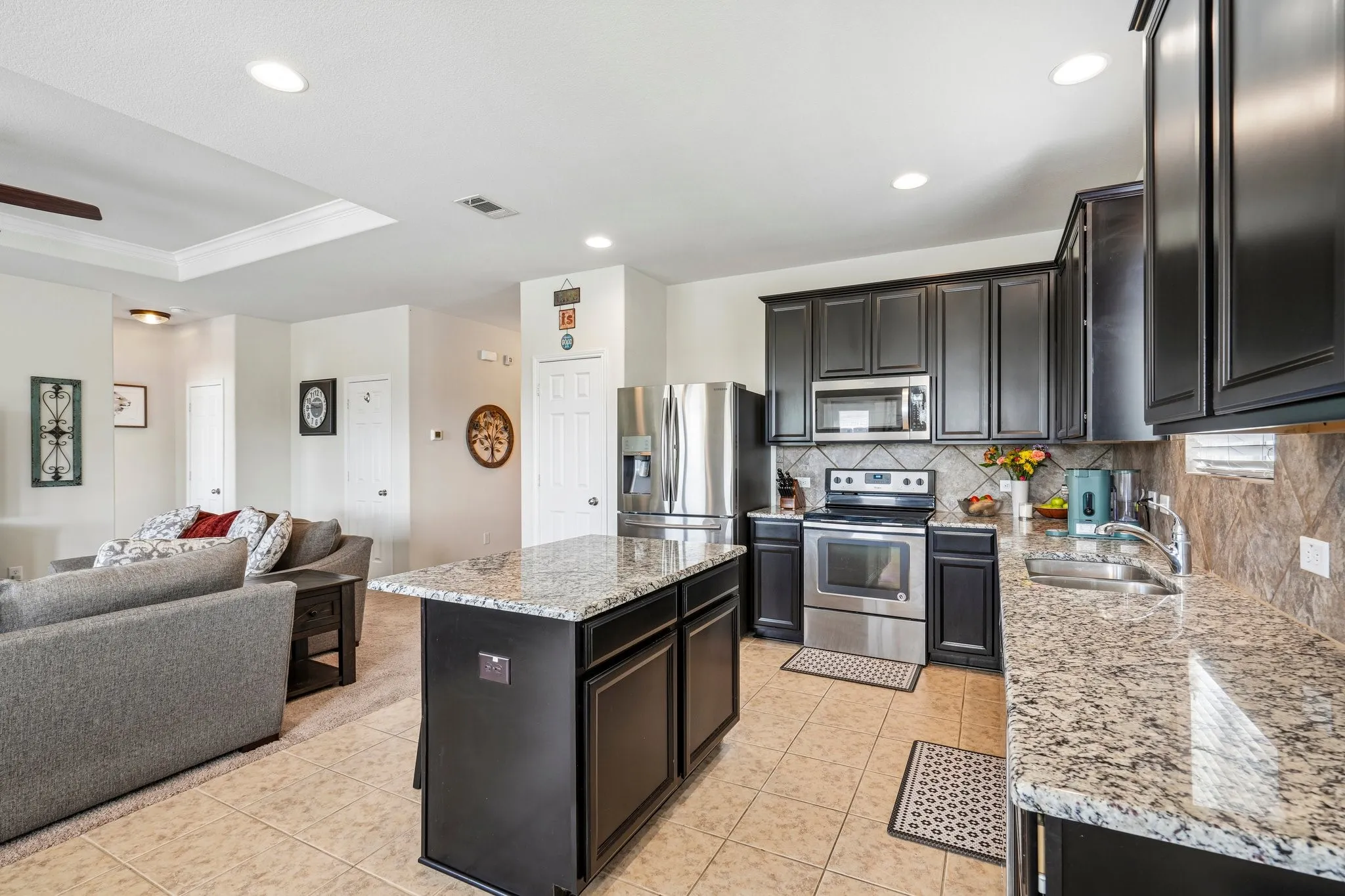 Kitchen featuring dark cabinetry, stainless steel appliances, granite countertops, and a tiled backsplash