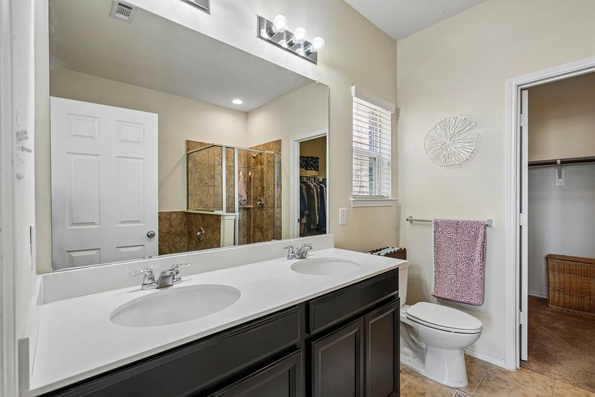 Dual vanity with undermount sinks and chrome fixtures, white countertop, and dark wood-finish cabinetry