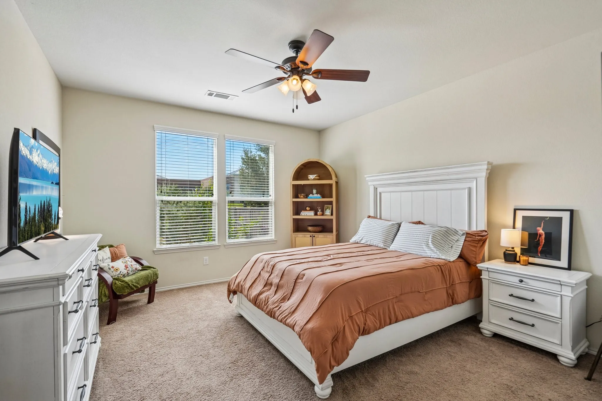 Plush carpeting, neutral wall tones, dual windows with blinds, and an overhead ceiling fan with lighting