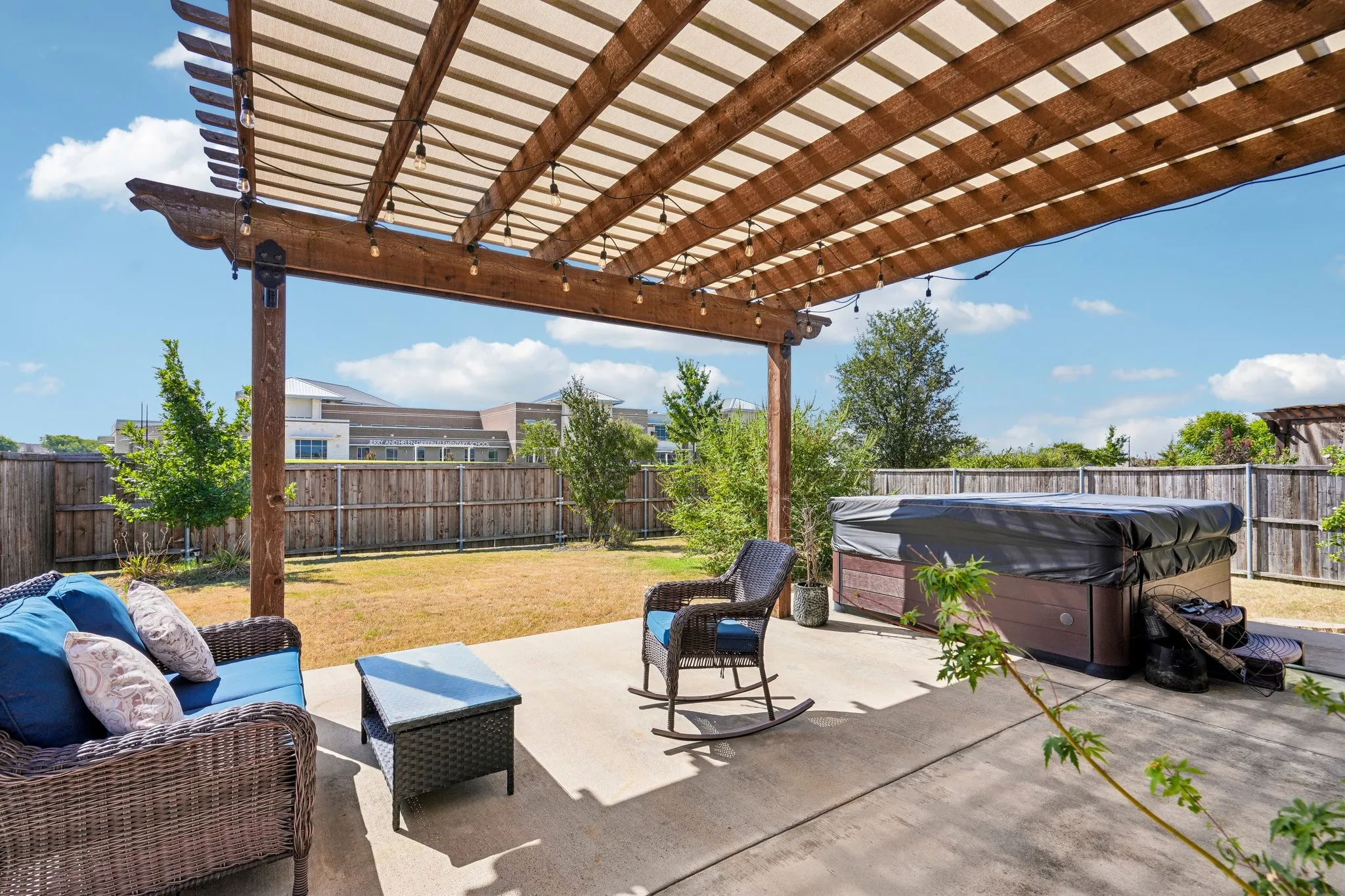 Expansive concrete patio featuring a wood pergola with integrated string lighting