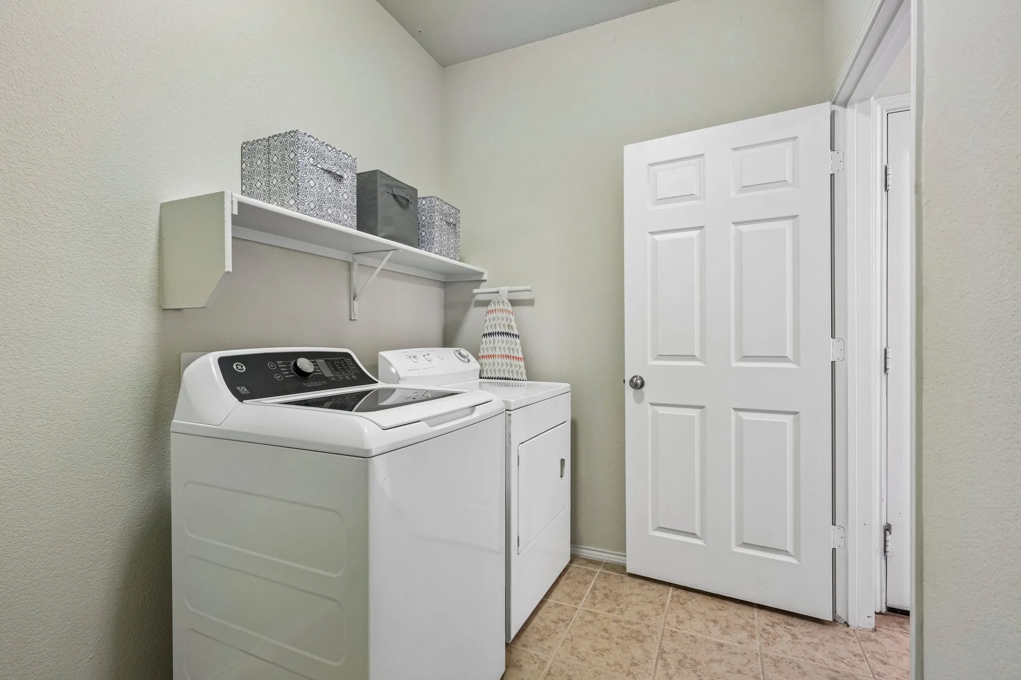 Built-in overhead shelving, two-panel interior door, and light-toned tile flooring