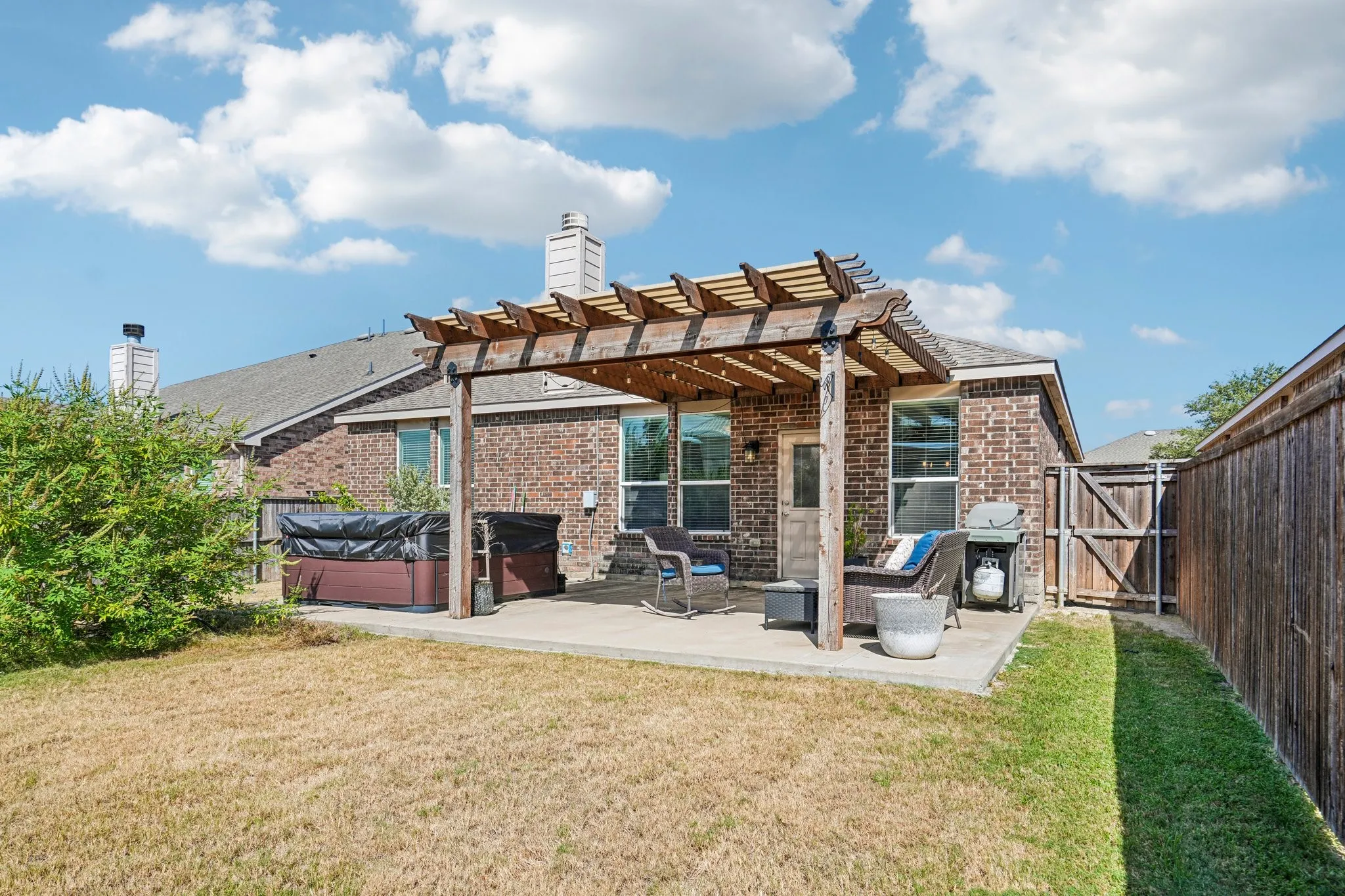Concrete patio featuring a wood pergola and a built-in hot tub