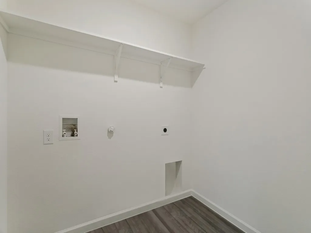 Laundry area featuring a utility hookup, wall-mounted shelving, and wood-finish flooring