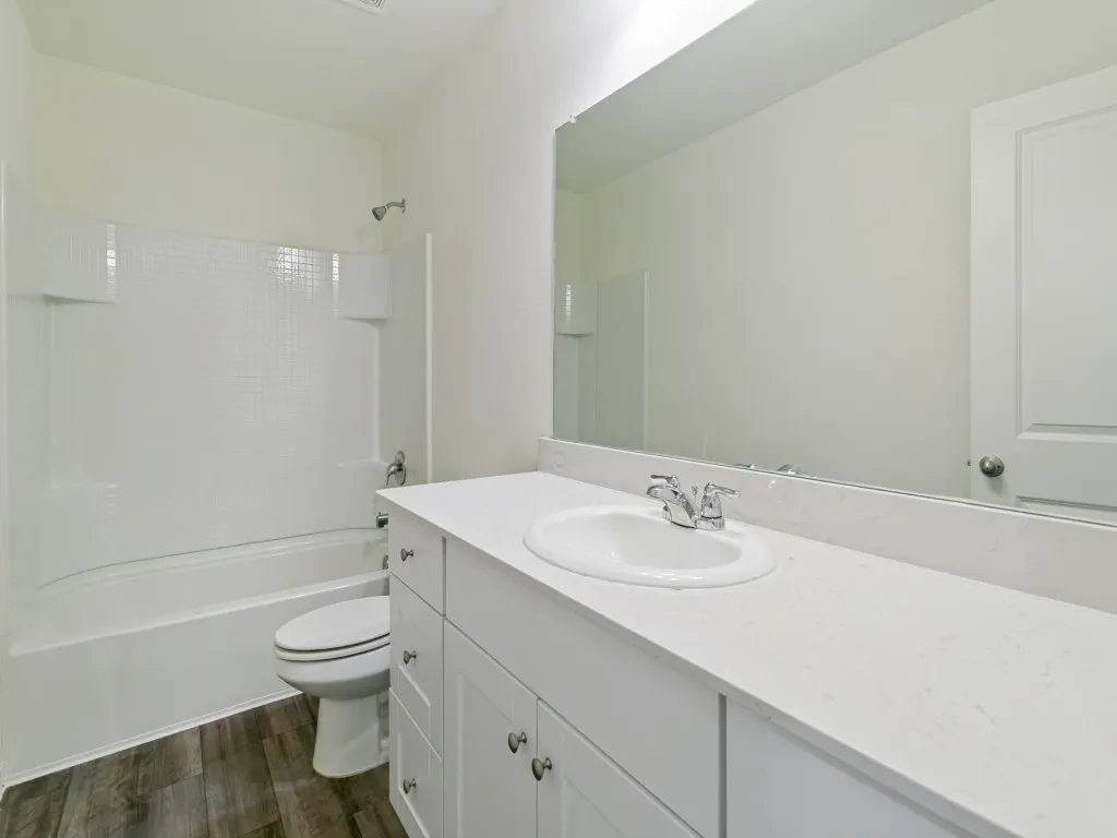 White vanity with a built-in sink, chrome fixtures, and a large wall-mounted mirror