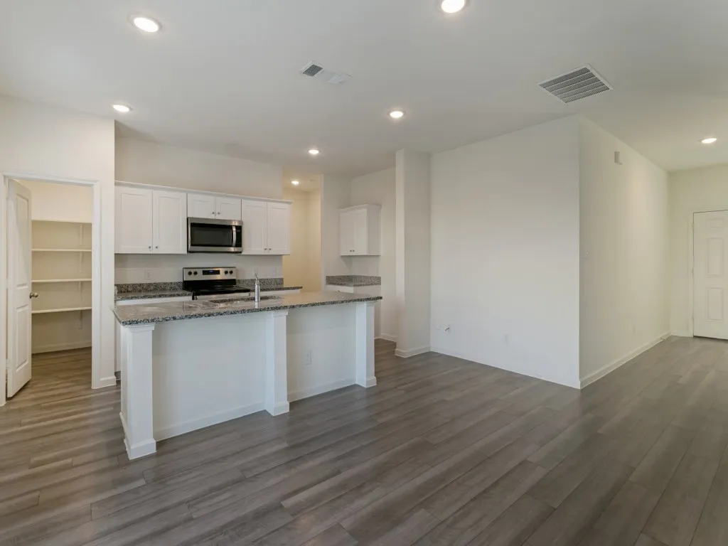 Kitchen with white cabinetry, granite countertops, stainless steel appliances, and a central island