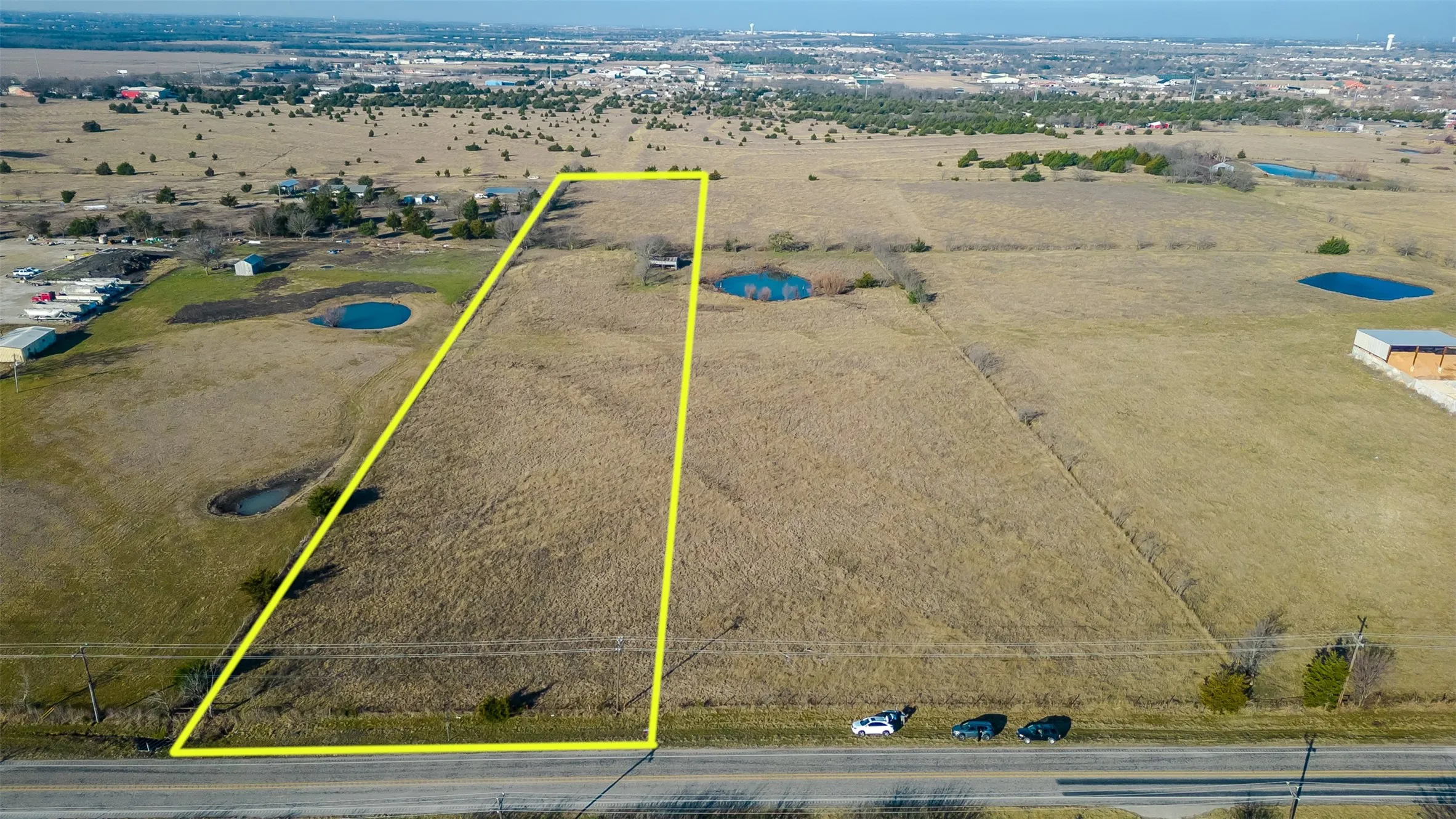 Expansive land parcel featuring open fields and a discernible pond