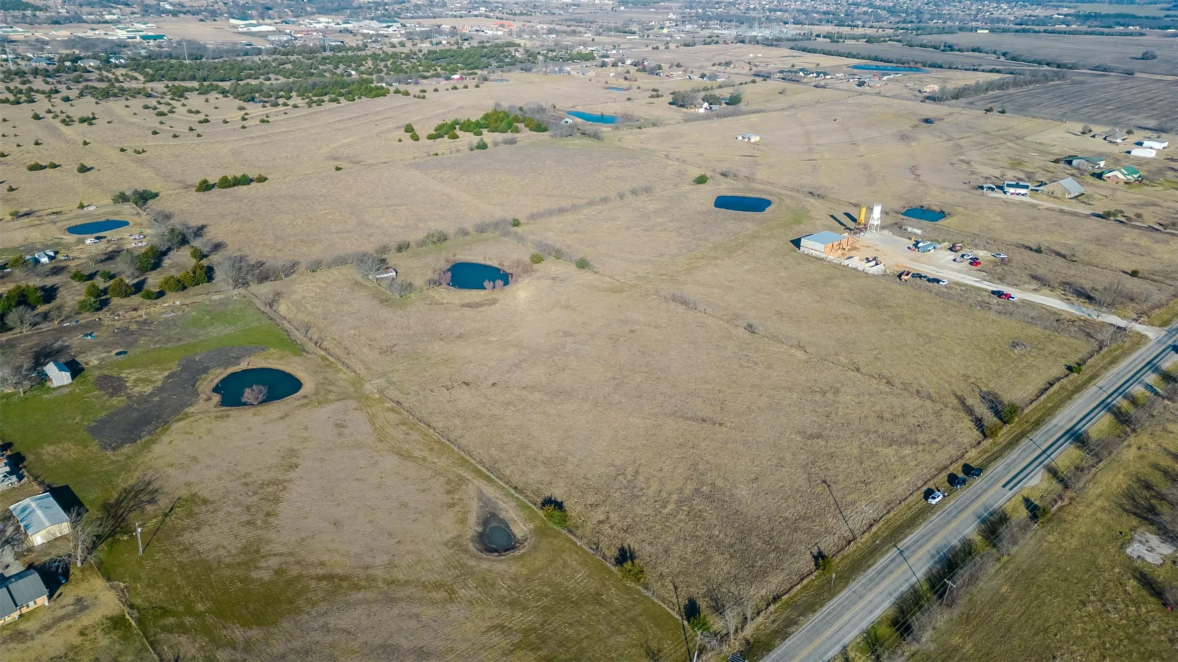 Expansive land parcel featuring scattered trees, and direct road frontage