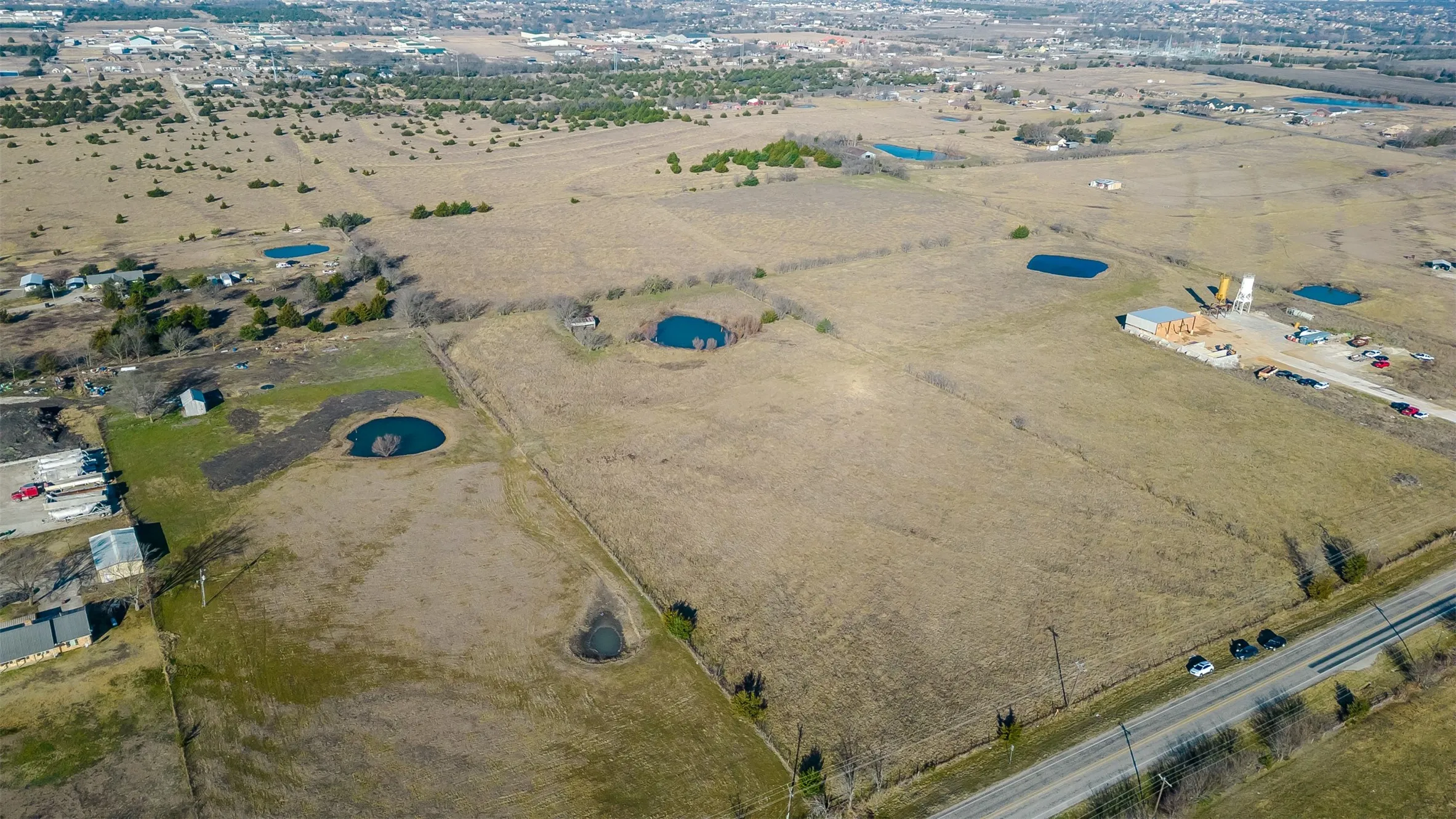 Expansive undeveloped land featuring scattered trees, and paved road frontage