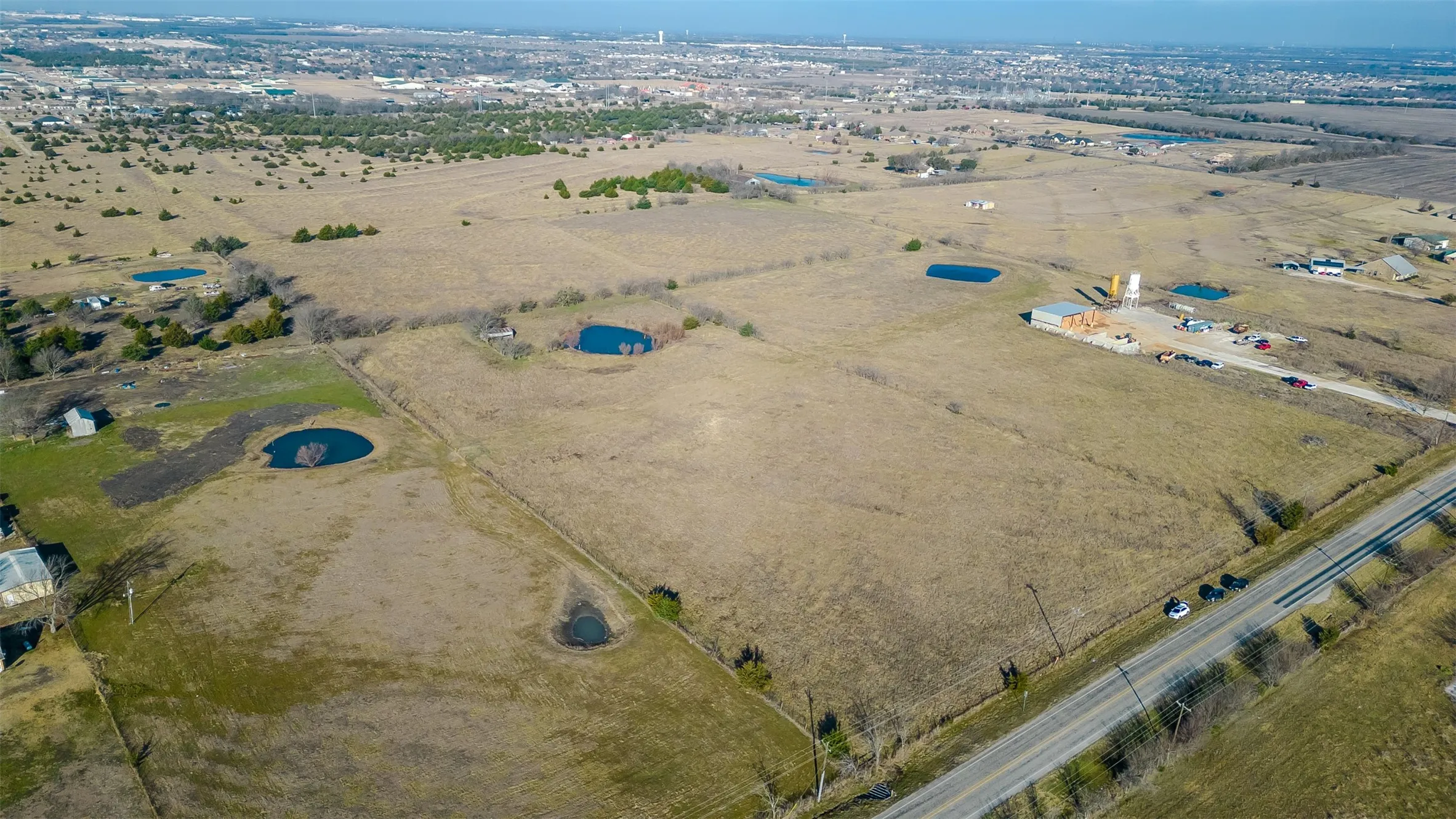 Expansive acreage featuring a paved road frontage, and distant tree lines