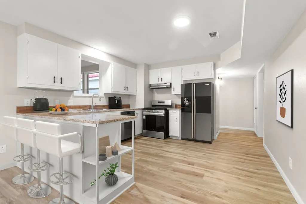 Kitchen featuring wood-finish flooring, white cabinetry, stainless steel appliances, and a pass-through window