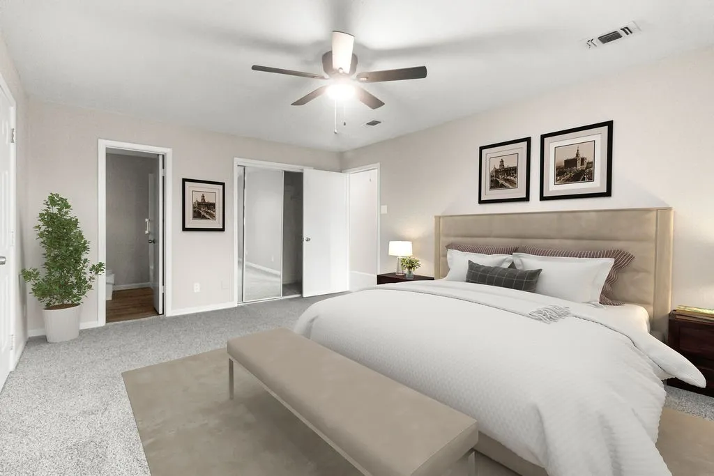 Carpeted flooring with light-toned walls, ceiling fan, and sliding mirrored closet doors